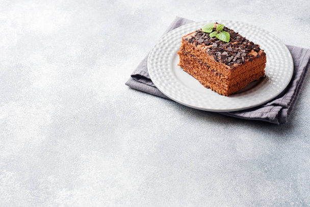 A piece of truffle cake with chocolate on a gray concrete background. Copy space - Zdjęcie, obraz