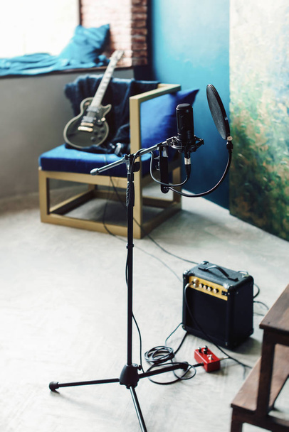 microfone condensador estúdio com filtro pop e anti-vibração montar gravação ao vivo. Parede azul, alto-falante e guitarra em um fundo
 - Foto, Imagem