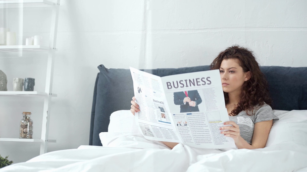 красивая девушка лежит в постели и читает деловую газету дома
 - Кадры, видео