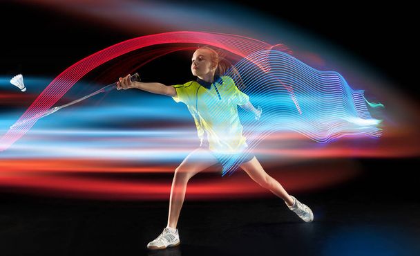 Young girl playing badminton over dark background - Foto, imagen