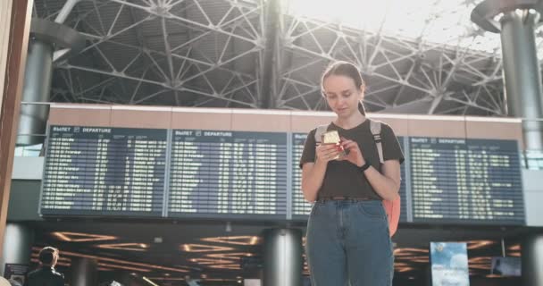 junge schöne Frau am Flughafen schreibt eine Nachricht - Filmmaterial, Video