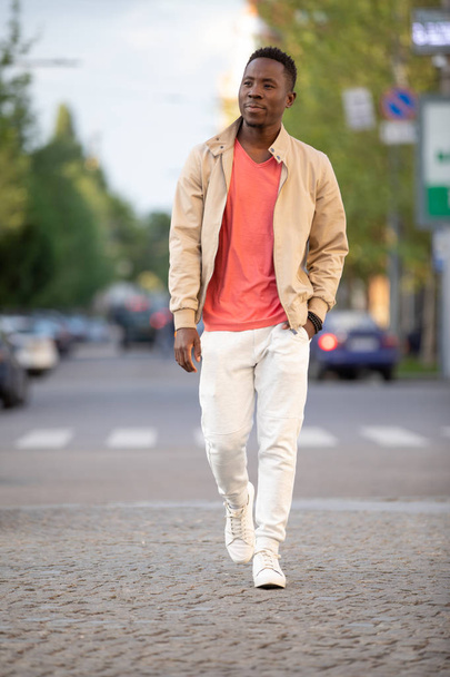 African american man in living coral t-shirt walking at city - Фото, зображення