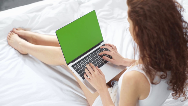 κορίτσι με πιτζάμες χρησιμοποιώντας φορητό υπολογιστή με πράσινη οθόνη στο κρεβάτι στο σπίτι - Πλάνα, βίντεο