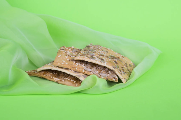 μπισκότα σε πράσινο πανί. Διαιτητικά μπισκότα με σπόρους. Σφολιάτας σε πράσινο φόντο - Φωτογραφία, εικόνα