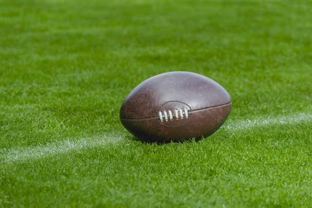 Amerikan futbolu, yeşil çim alan arka plan üzerinde rugby topu - Fotoğraf, Görsel