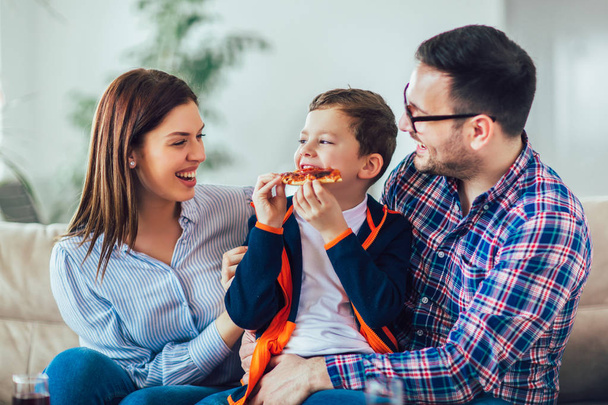 Portrait of happy family eating pizza while sitting on sofa at h - Φωτογραφία, εικόνα