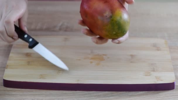 Vrouwelijke chef-koks handen slice mango op houten snijplank. - Video