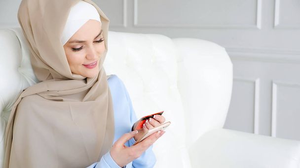 Hijab Müslüman kadın bir kredi kartı ve akıllı telefon ile online satın alıyor. - Fotoğraf, Görsel