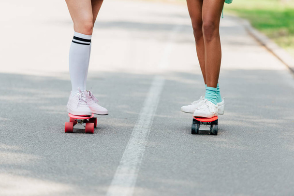 visão parcial de duas meninas skate em tábuas de centavo na estrada
 - Foto, Imagem