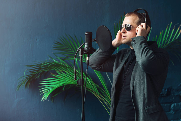 Primer plano de un hombre cantante en un auricular grabando una canción en un estudio en casa
 - Foto, Imagen