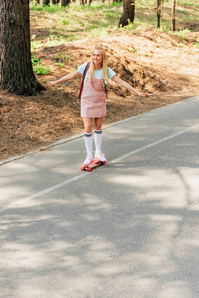 Blonde Mädchen in Kniestrümpfen skateboarden auf der Straße in voller Länge - Foto, Bild