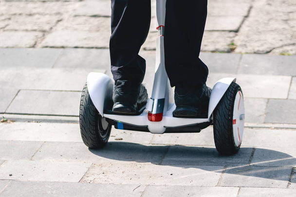 Feet of girl riding electric mini hoverboard scooter on the road. Ecological city transportation on battery power. - Φωτογραφία, εικόνα