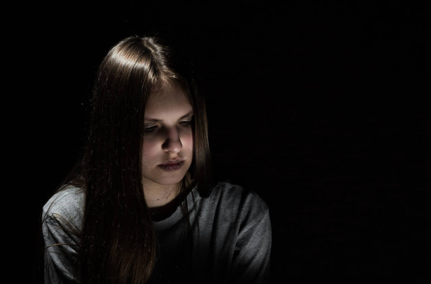 portrait of young teenager brunette girl with long hair in the Gothic style on a black background with copy space - Foto, Imagen
