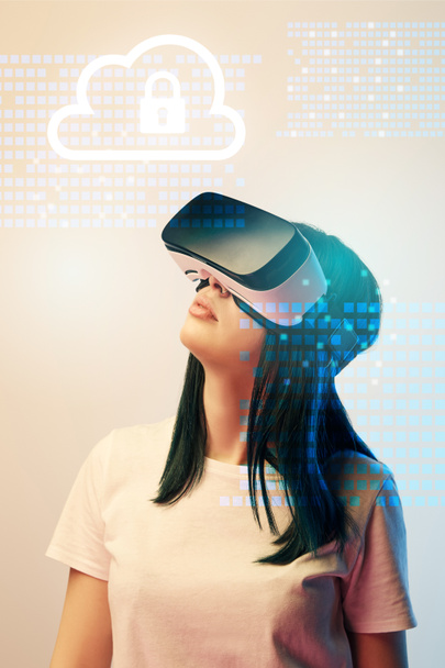 young woman in virtual reality headset looking at internet security illustration on beige background - Photo, Image