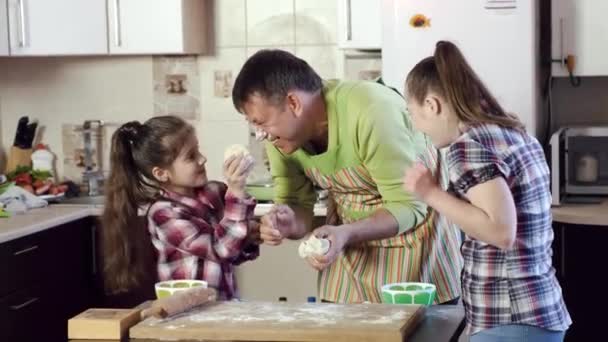 ο πατέρας επευφημεί κόρες και σιαγόνες μικρά πυκνά κομμάτια ζύμης - Πλάνα, βίντεο