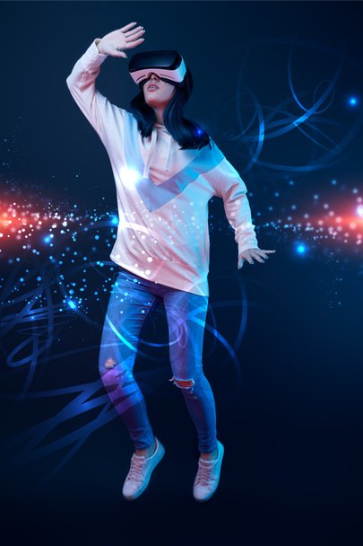 young woman in virtual reality headset flying in air among glowing data illustration on dark background  - Photo, Image