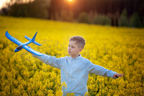 Child plays with a toy airplane in the sunset and dreams of journey in summer day. - Foto, Bild