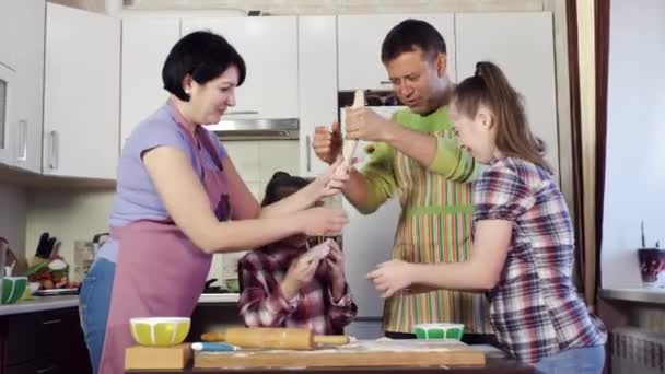 sisters and parents stretch thick dough above cooking table - Footage, Video