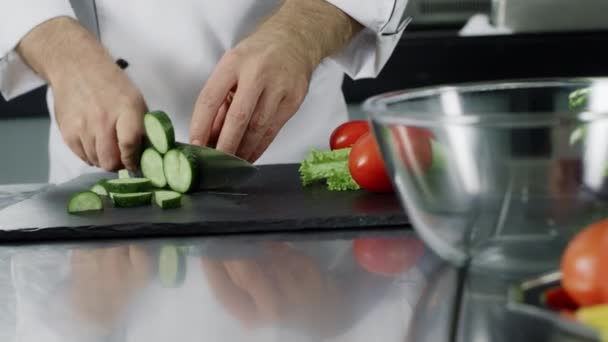 Mies kokki leikkaa kurkkua keittiön ravintolassa. Kokki käsi valmistelee tuoretta salaattia
 - Materiaali, video