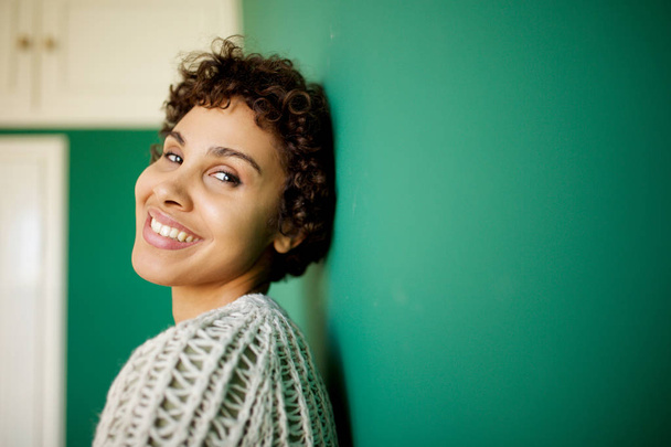Close up side portrait of happy african american woman smiling against green wall - Φωτογραφία, εικόνα