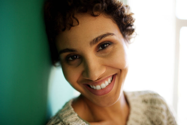 Portrait en gros plan d'une femme afro-américaine souriante appuyée contre un mur
 - Photo, image