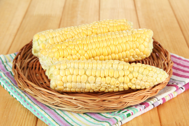 Fresh corn on wicker mat, on wooden background - Foto, Imagen