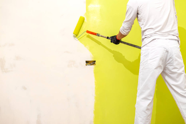 Маляр использовать краску ролика на новой восстановленной стене
 - Фото, изображение