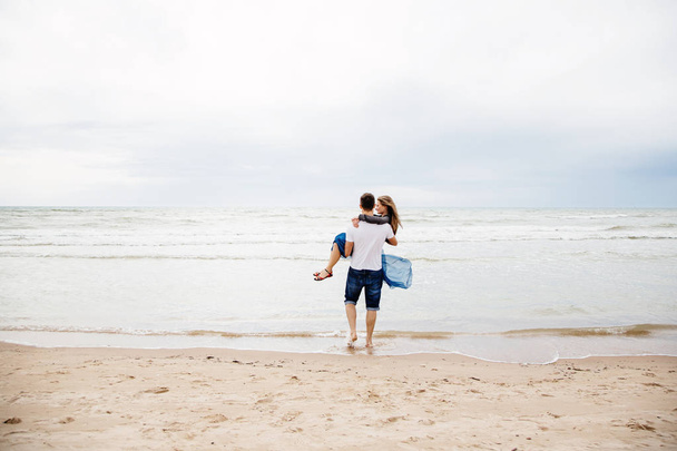 Casal amoroso na praia. Homem segurando uma mulher em suas mãos
. - Foto, Imagem