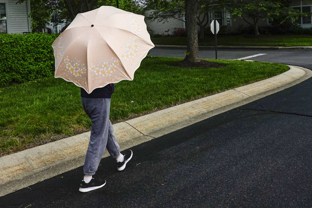 Solomons Island, Maryland, USA Eine Frau geht mit einem Regenschirm gegen die Sonne auf die Straße. - Foto, Bild