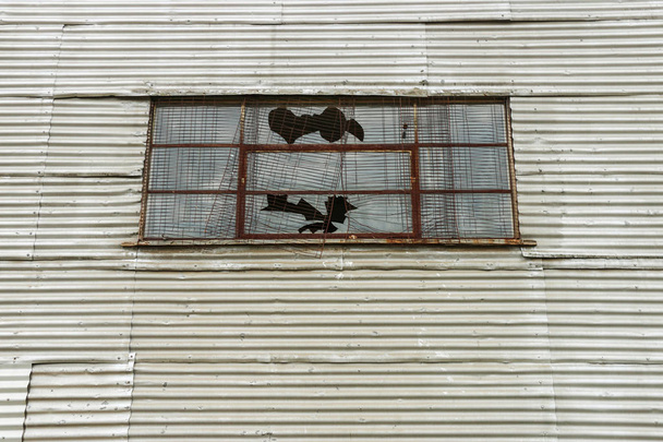 broken window on abandoned corrugated iron building - Photo, Image