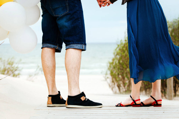 Szerető pár állva egy mólón a strandon léggömbök.  - Fotó, kép