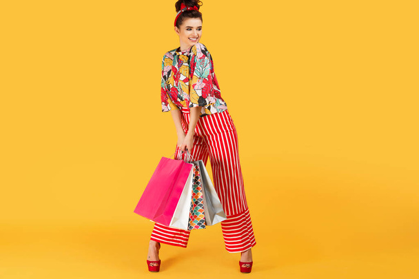 Full lenhts photo of young happy caucasian woman in casual colorful clothes holding bags and shopping over orange background. Shopping and sales concept. - Photo, Image