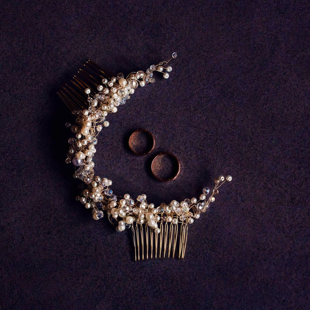 Biżuteria ślubna ułożone na stole. Pearl Akcesoria do włosów i dwa obrączki. Widok z góry na dół. - Zdjęcie, obraz