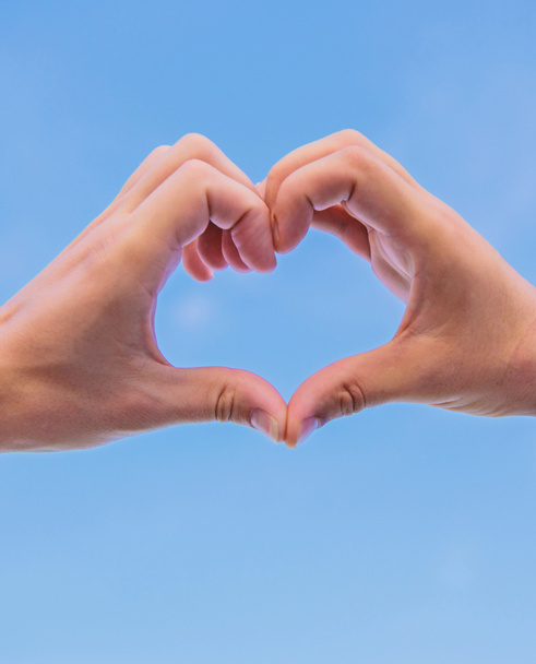 Hands put together in heart shape blue sky background. Love symbol concept. Hand heart gesture forms shape using fingers. Male hands in heart shape gesture symbol of love and romance - Fotoğraf, Görsel