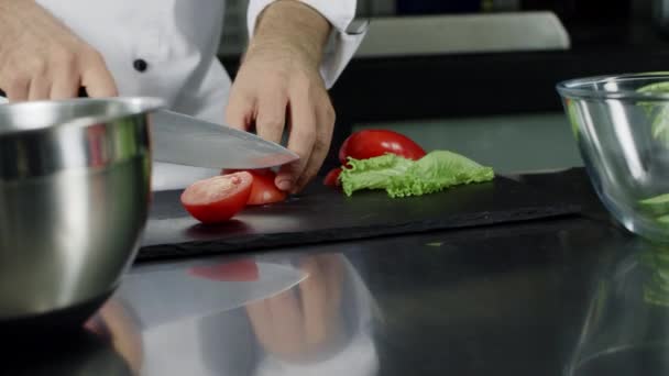 Kokki kokkaa tuoretta salaattia keittiössä. Lähikuva kokki kädet leikkaamalla tomaatti
. - Materiaali, video