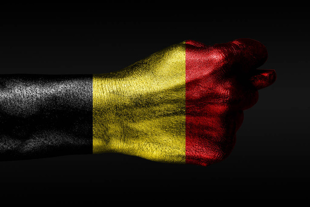 塗装されたベルギーの旗を持つ手は、イチジク、侵略の兆候、意見の相違、暗い背景の紛争を示しています. - 写真・画像