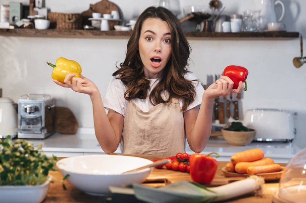 Beautiful young woman wearing apron cooking vegetables - Valokuva, kuva