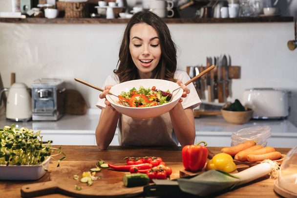 Beautiful young woman wearing apron cooking vegetables - Φωτογραφία, εικόνα