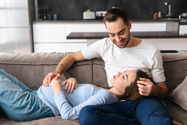 Happy young pregnant couple relaxing on a couch - Foto, afbeelding