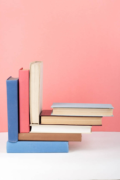 Open book, hardback colorful books on wooden table, red, pink background. Back to school. Copy space for text. Education business concept. - Foto, afbeelding