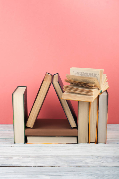 Open book, hardback colorful books on wooden table, red, pink background. Back to school. Copy space for text. Education business concept. - Photo, image