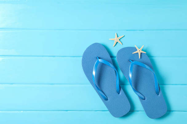Flip flops and starfishes on color wooden background, space for  - Zdjęcie, obraz