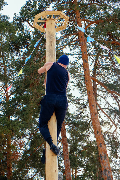 A man climbs on a pillar at Shrovetide - Foto, afbeelding