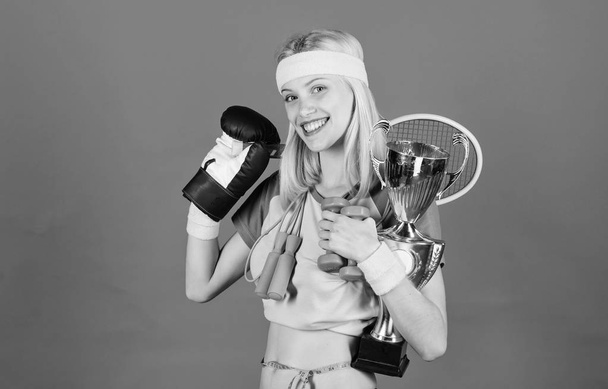 Sport shop assortment. Girl successful modern woman hold golden goblet of sport champion and equipment blue background. How to find time for everything. Sport equipment store. Sport for every day - Foto, Imagen