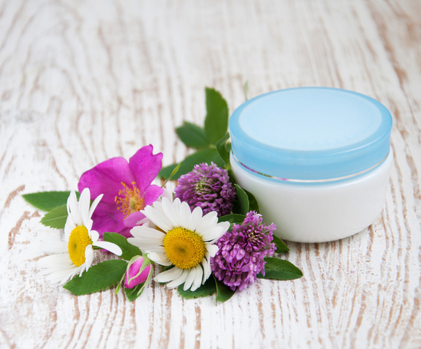 container with cream and wild flowers - Foto, imagen