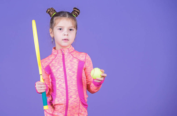 Childhood and active games. Sport upbringing. Small cutie likes tennis. Little baby sporty costume play tennis game. Teach me how to play tennis. Girl cute child double bun hairstyle tennis player - Photo, image