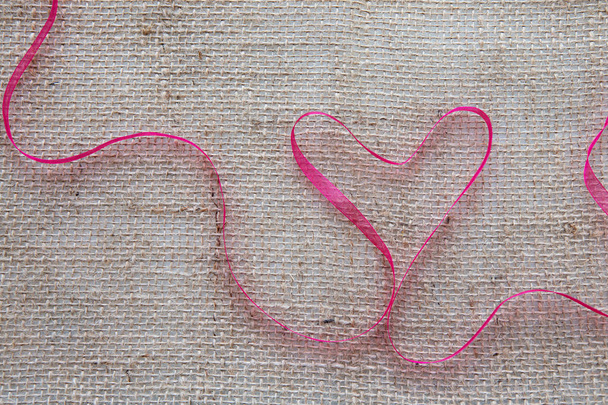 Red heart ribbon isolated on brown cloth background. - Photo, Image