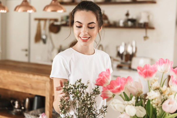 Happy young student girl posing indoors near flowers. - Foto, Imagem