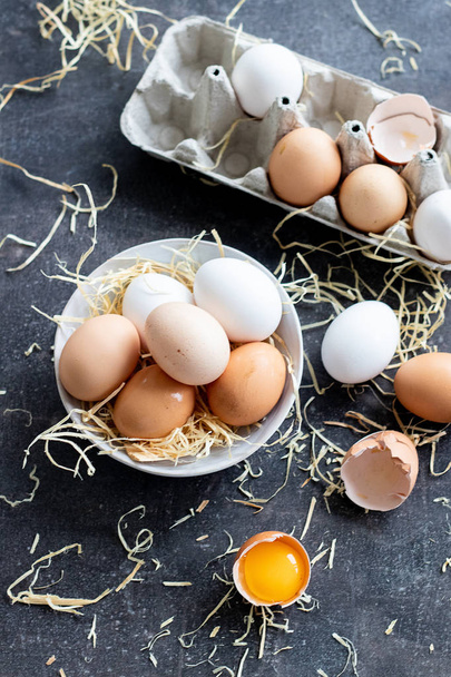 Świeże organiczne surowe jaja, biały, beżowy i brązowy, jeden jest pęknięty - Zdjęcie, obraz