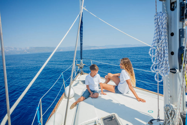 Boy with his sister on board of sailing yacht on summer cruise. - 写真・画像